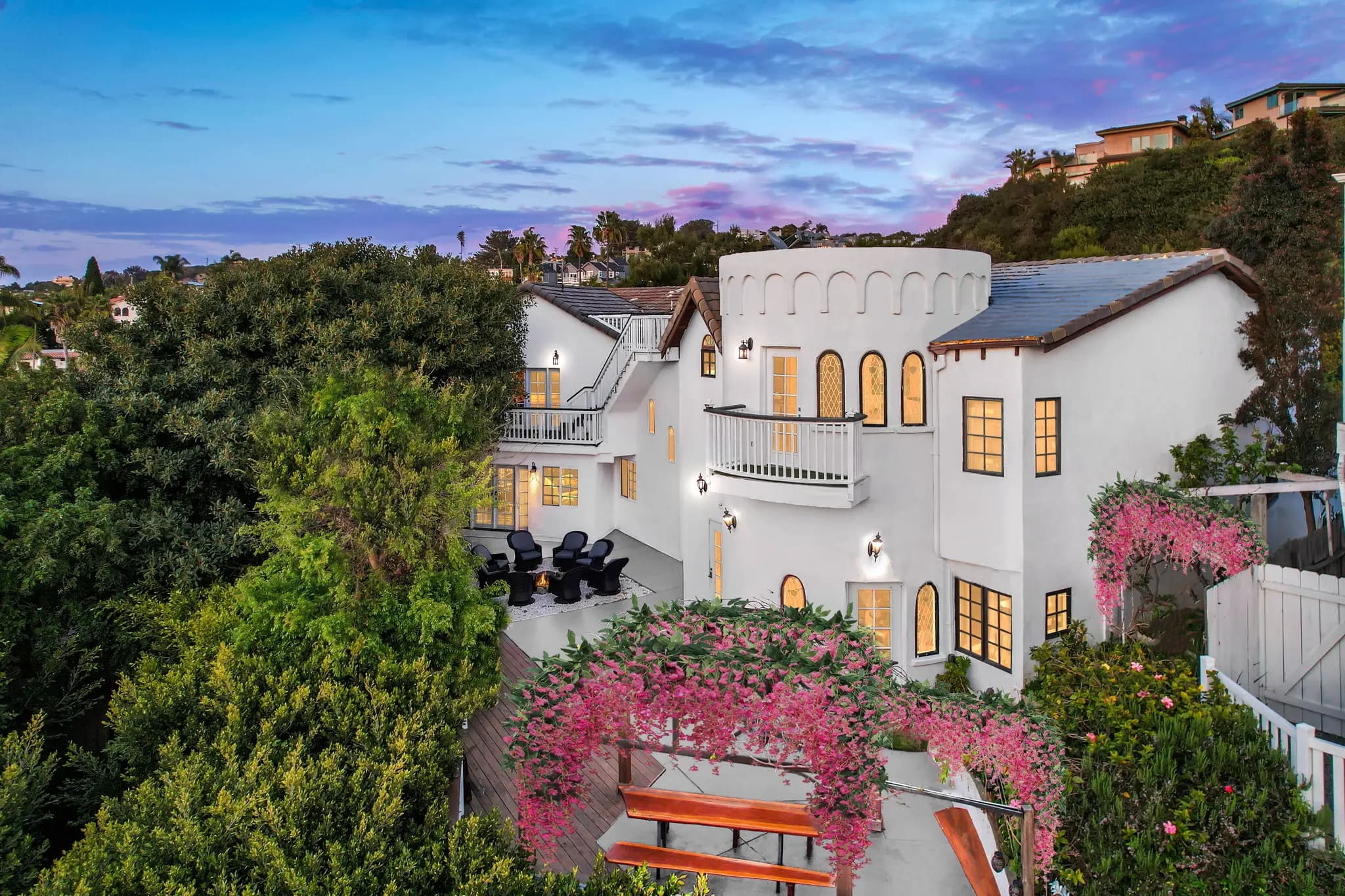 Exterior view of 915 Highland Drive-105, a white Mediterranean-style home with arched windows, multiple balconies, and a lush garden surrounded by greenery.